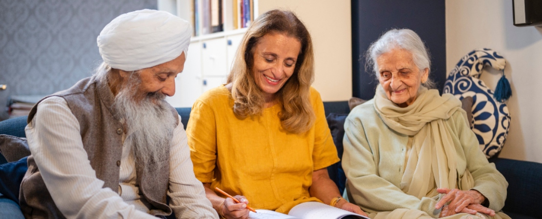 A researcher sitting with two elderly members of the community